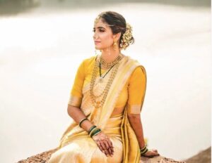 Maharashtrian bride sitting by a water body, wearing a Saadee, Mundavlya, and, Bangdya